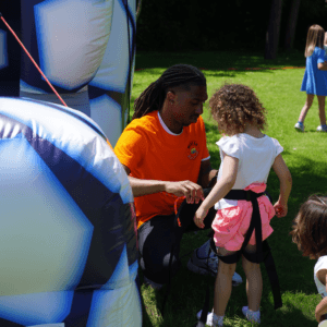 Un animateur spécialisé Mister Bounce aidant un enfant à s'amuser en toute sécurité dans un château gonflable.