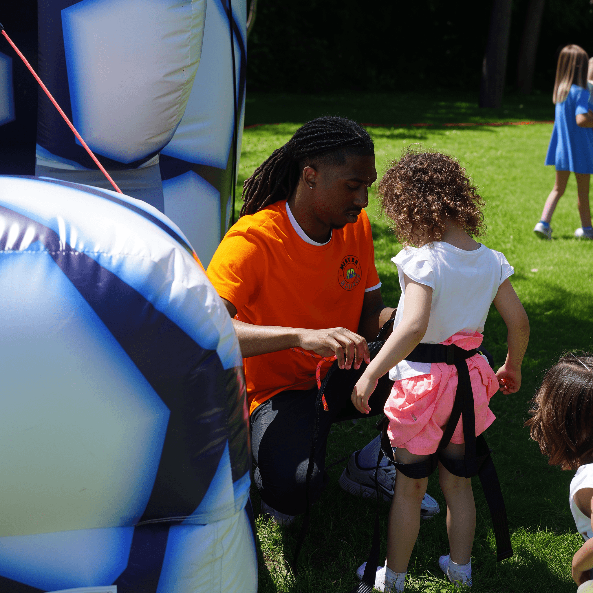 Un animateur spécialisé Mister Bounce aidant un enfant à s'amuser en toute sécurité dans un château gonflable.