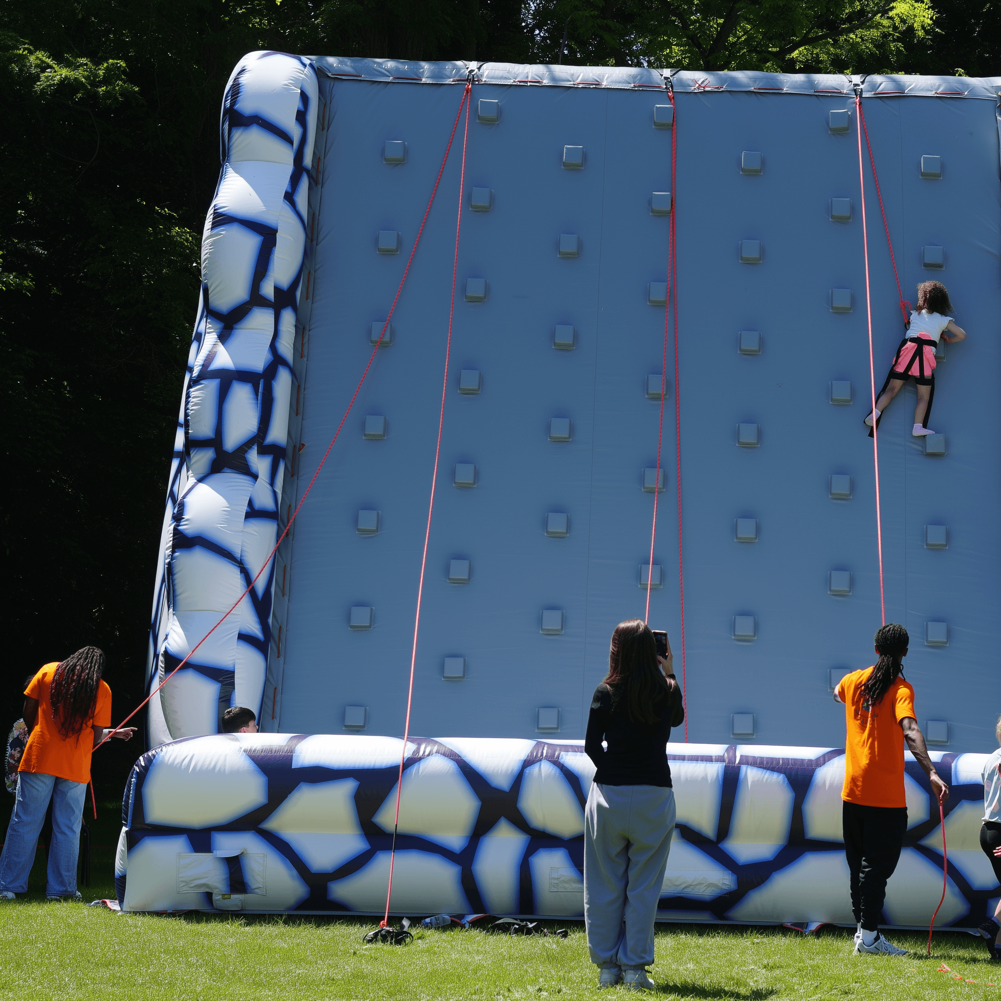 Équipe d'animateurs Mister Bounce encadrant des enfants sur un mur d'escalade gonflable sécurisé.